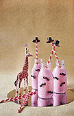 Himbeersmoothie in Flaschen, Strohhalme mit Hütchen und Giraffenfigur