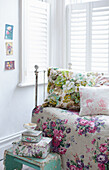 Daybed with floral fabrics and vintage tins and teacup.