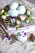 Easter eggs flowers and feathers in a nest with fabric