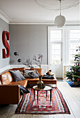 Cognacfarbene Ledercouch und Kelim-Teppich im Wohnzimmer mit hellgrauen Wänden