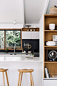 Bar stool at the counter with shelf as room divider in modern kitchen