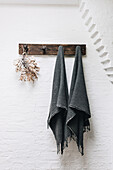 Tasseled dark grey towels on rustic hook rail