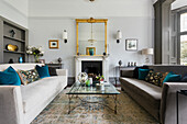 Elegant salon with upholstered sofas and antique mirror above the fireplace