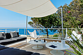 Terrace with white tables, classic chairs, bench, awning and sea view