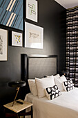 Double bed, above it modern pictures in the bedroom with black wall