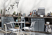 Filigree table with chairs in front of outdoor kitchen made of galvanised steel