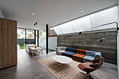 Designer-Sitzmöbel im Wohnraum mit Betonwand, dahinter Essbereich