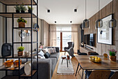 Open plan living room with shelving, dining area, upholstered sofa, armchair and TV