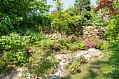 Lush summer garden with natural stones and dry stone wall