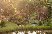 View across pond to patio in a lush garden