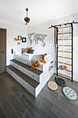 Loft bed with storage space and wall bars with gymnastics equipment in child's bedroom