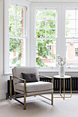 Seating area with upholstered armchair and side table in bay window