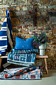 Bench with rug, cushion and blanket in blue tones in front of natural stone wall
