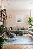 View into living room with book shelves, grey sofas and pink wall
