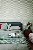 Double bed in blue-green shades in bedroom with matching wallpaper