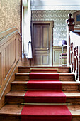 Old wooden staircase with red carpet