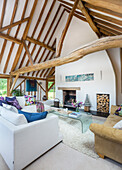 Seating and glass coffee table in front of fireplace in converted barn with wooden beams