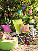 Deck chair, cushions, pillows, lanterns and paper lanterns on summer terrace
