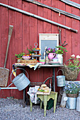 Garden table with tomatoes, crockery and a dessert stand outside of a wooden house