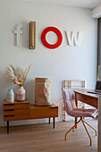 Flow' letters on white wall, below retro sideboard in living room