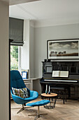 Blue armchair with footstool and piano in music room