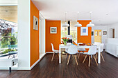 Weißer Tisch und Stühle im Essbereich mit orangefarbenen Wänden