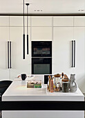 White fitted kitchen with black appliances and island counter