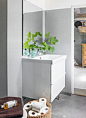 Washbasin with base cabinet and leafy branch in the bathroom