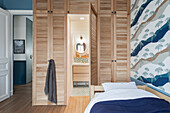 Bedroom with en suite bathroom, slatted wardrobes and patterned wallpaper