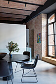 Dining table with black chairs and industrial-style brick wall