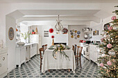 Dining table in kitchen with Christmas table decorations and decorated Christmas tree