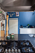 Kitchen with blue wall, large pepper mill and gas hob