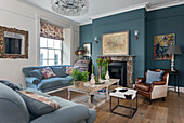 Upholstered furniture and leather armchairs in front of fireplace in a living room with blue wall