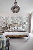 Double bed in front of patterned wallpaper in light bedroom