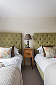 Two single beds with upholstered headboard, antique bedside table in between