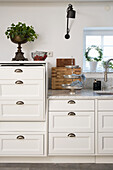 Weiße Küchenzeile mit Marmorplatte, darüber schwarze Wandleuchte