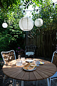 Round patio table with chairs, lanterns above in the garden