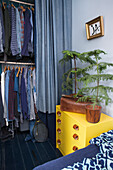 Fir trees on a yellow chest of drawers in front of an open wardrobe