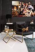 Anthrazitfarbener Sessel und Beistelltisch vor dunkler Wand mit großem Bild