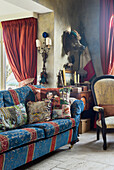 Patchwork cushions on blue and red sofa in vintage-style living room with flea-market finds