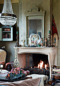 Chandelier in living room with open fireplace and vintage-style decorations