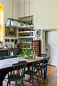 Küche mit Esstisch mit dunkelgrünen Stühlen und länglicher Glaspendelleuchte