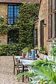 Idyllische Terrasse mit Gartentisch vor historischem Gebäude mit Efeubewuchs