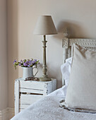 Vintage-style bedside table with lamp and flower vase