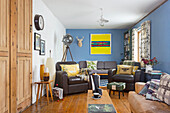 Living room with blue walls, leather sofas and colorful wall art