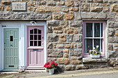 Traditionelles Steingebäude mit rosa Tür und Fensterläden und Blumendekoration