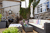 Terrace corner with rattan furniture, grill and historic stone wall