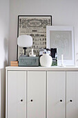 White sideboard cabinet with decor and framed illustrations