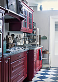 Dark red kitchen cupboards with vintage utensils