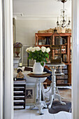 Weiße Rosen in Krugvase auf rundem Beistelltisch im Wohnzimmer mit Antikmöbeln